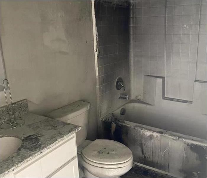 Bathroom vanity, toilet stool, and tub damaged by smoke and soot