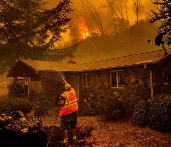 A man hosing down a house fire